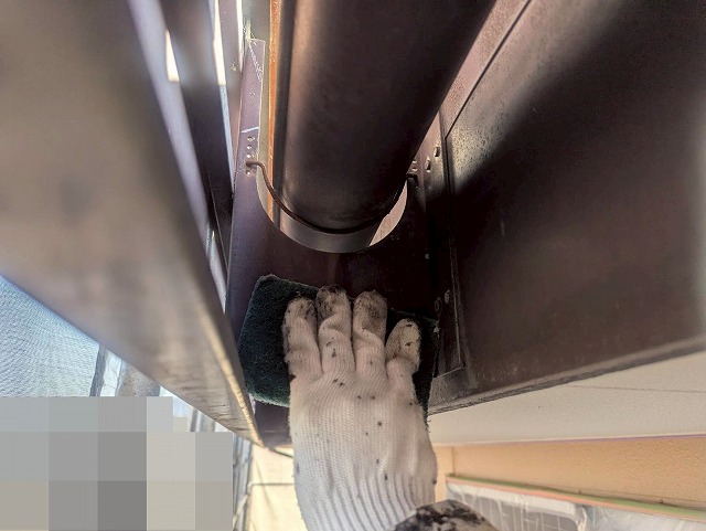 西八代郡市川三郷町で色あせた雨樋（軒樋・竪樋）を塗装する際に、ケレン作業（目粗し）を行う様子