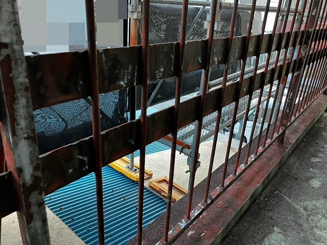 甲府市で屋上の鉄部手すり・鉄部柵に、電動工具（サンダー）でケレン作業（研磨・目粗し）する様子