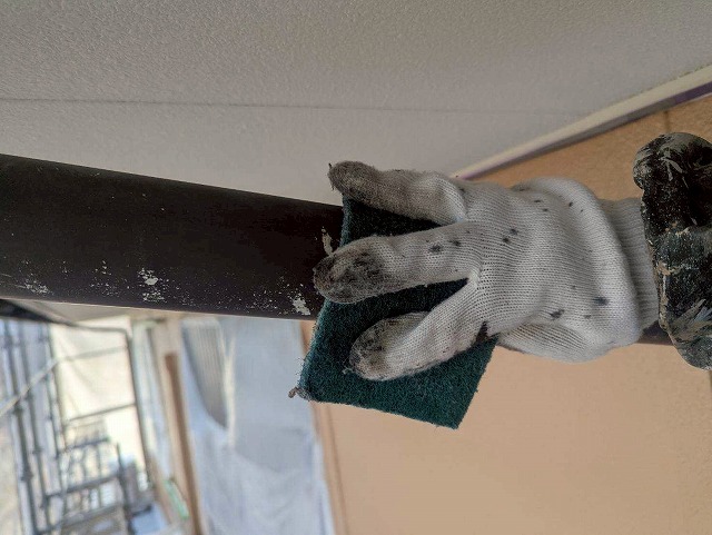 西八代郡市川三郷町で色あせた雨樋（軒樋・竪樋）を塗装する際に、ケレン作業（目粗し）を行う様子