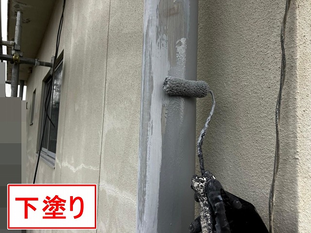 甲府市で塗膜がはがれた竪樋（配管）の塗装で下塗りを行う様子