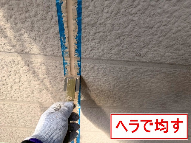 山梨市でサイディング目地にシーリングを充填しヘラで均す様子（シーリング打ち替え工事）