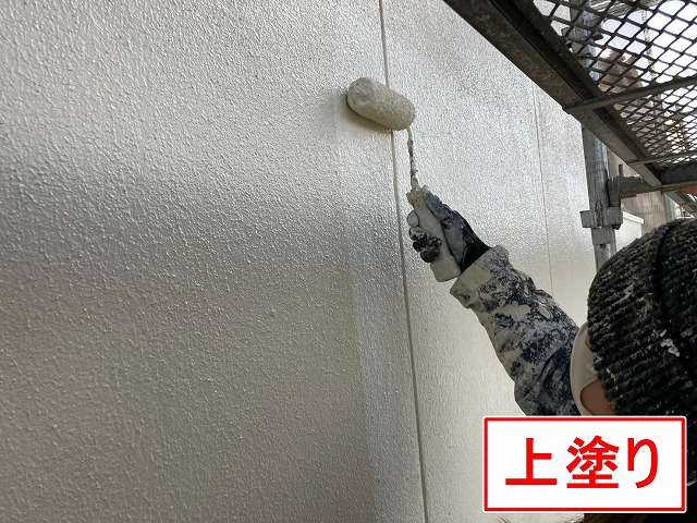 甲府市で下塗り後のモルタル外壁に仕上げ塗装（中塗り）を行う様子