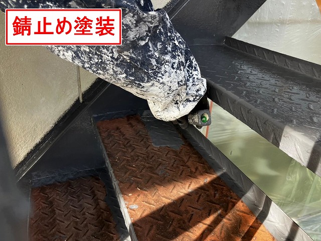 甲府市で塗膜剝がれ・錆びの発生した鉄部階段にケレン作業後、錆止め塗装（下塗り）を行う様子