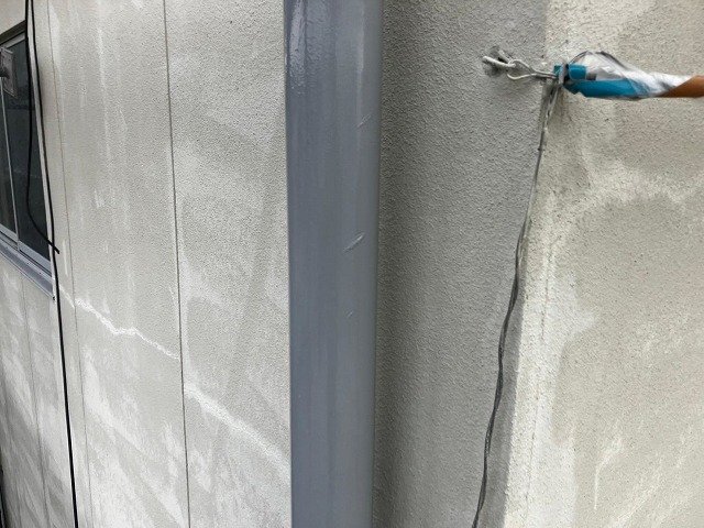甲府市で塗膜がはがれた竪樋（配管）の塗装で下塗りを行う様子