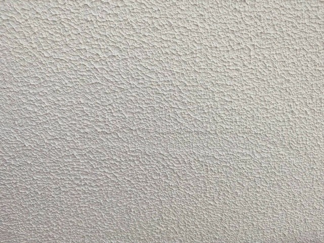 笛吹市でモルタル外壁の塗膜が浮いた箇所を補修する様子