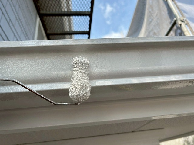 南アルプス市で雨樋（軒樋）にローラーで塗装する様子