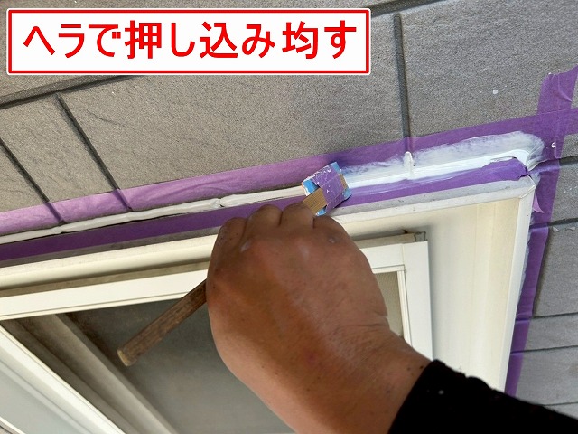 南アルプス市で窓・ドア・換気フードのサッシ廻りにシーリング材を押し込んで均す様子（シーリング増し打ち工事）