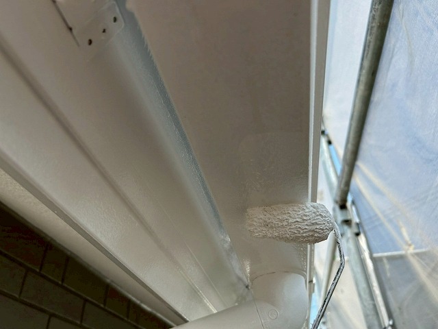 南アルプス市で雨樋（軒樋）にローラーで塗装する様子