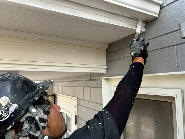 南アルプス市で雨樋（軒樋）にひらぺったい刷毛で塗装する様子