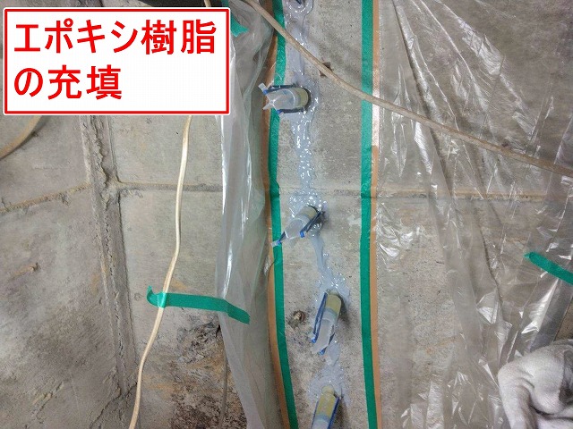 西八代郡市川三郷町で倉庫の外壁基礎をエポキシ樹脂の充填でひび割れ補修する様子