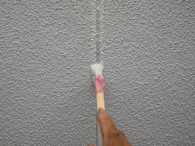 北杜市でモルタル外壁塗装の際に刷毛を使用して塗装する様子