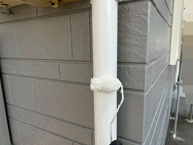 南アルプス市で雨樋（竪樋）にローラーで塗装する様子